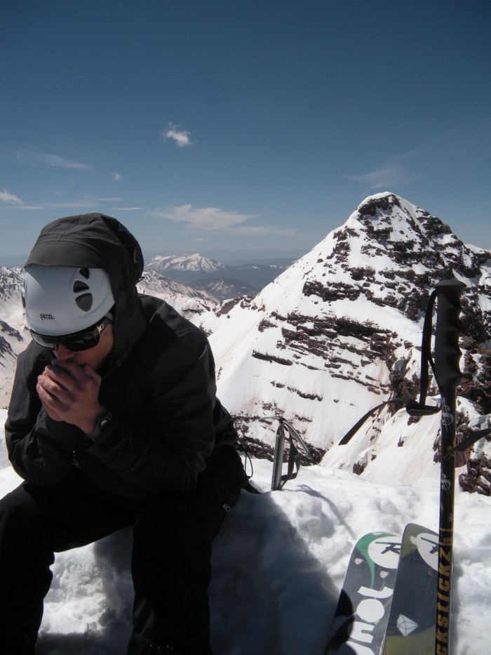Tyler warming his hands on the summit